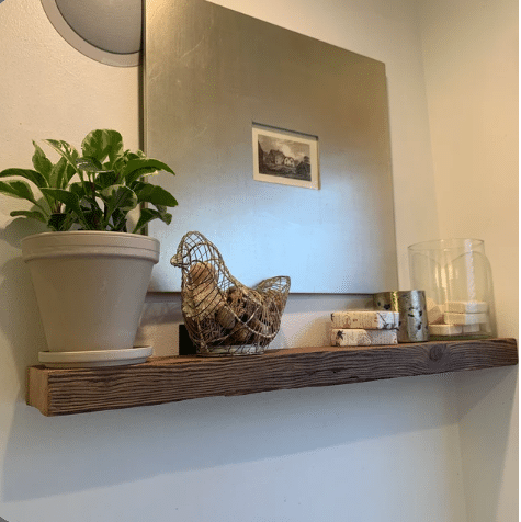 reclaimed barnwood floating wall shelf without finish applied. Grain patterns and knots are visible in the wood. 