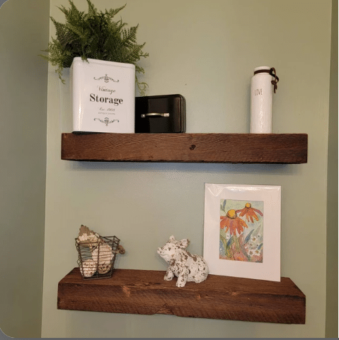 two reclaimed barnwood floating shelves on a wall. Grain pattern is displayed with other distressed characteristics.