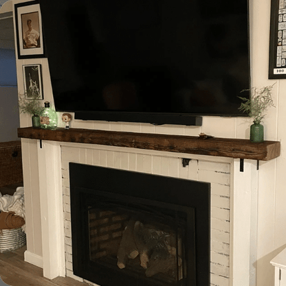 a reclaimed wood floating fireplace mantel in the oil finish. Mantel is mounted above a fireplace but below a television. The oil finish brings out the grain patterns in the face of the mantel.