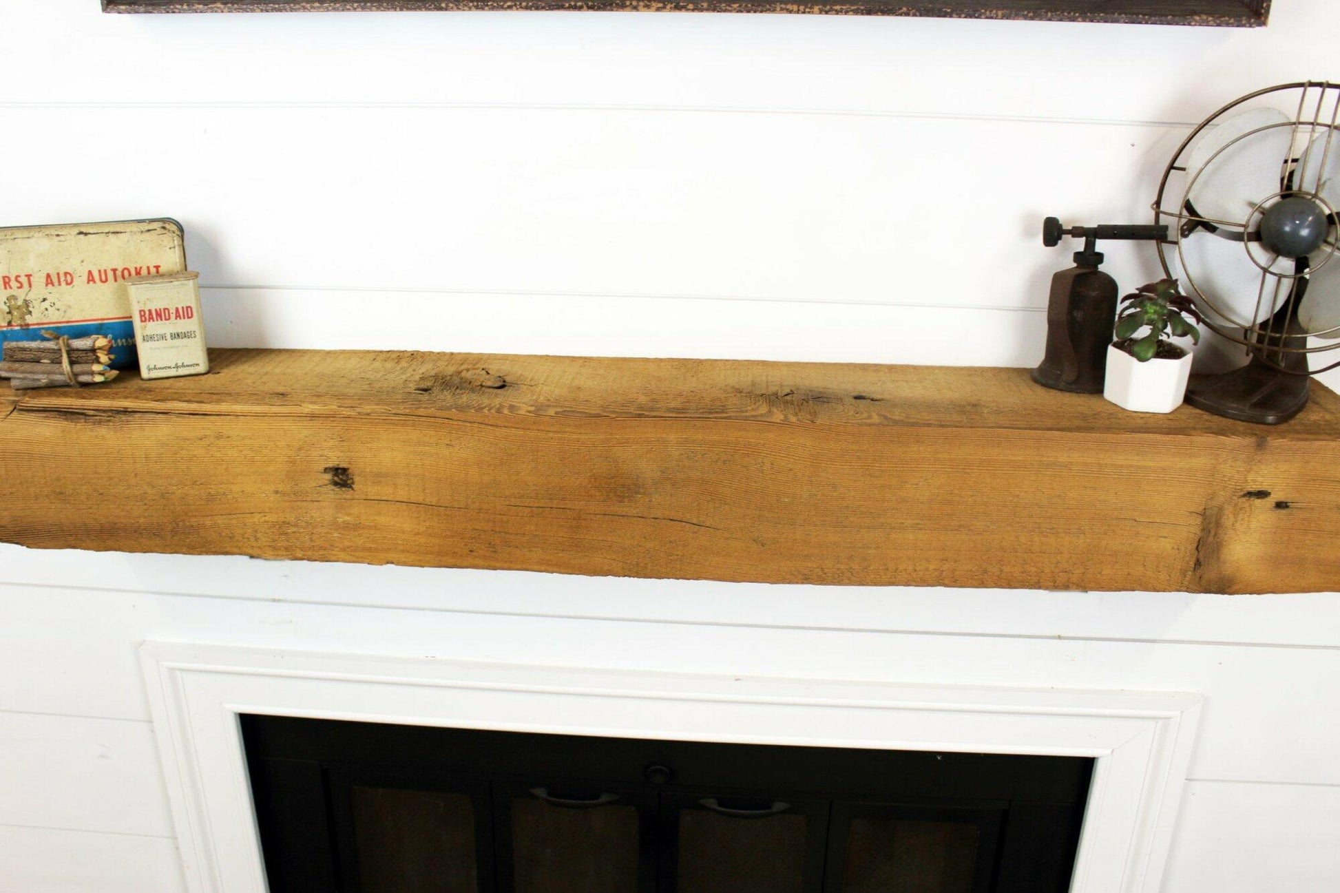 a close up of a reclaimed wood fireplace mantel in its natural color. The woods grain pattern, texture, knots, and nail holes are displayed.