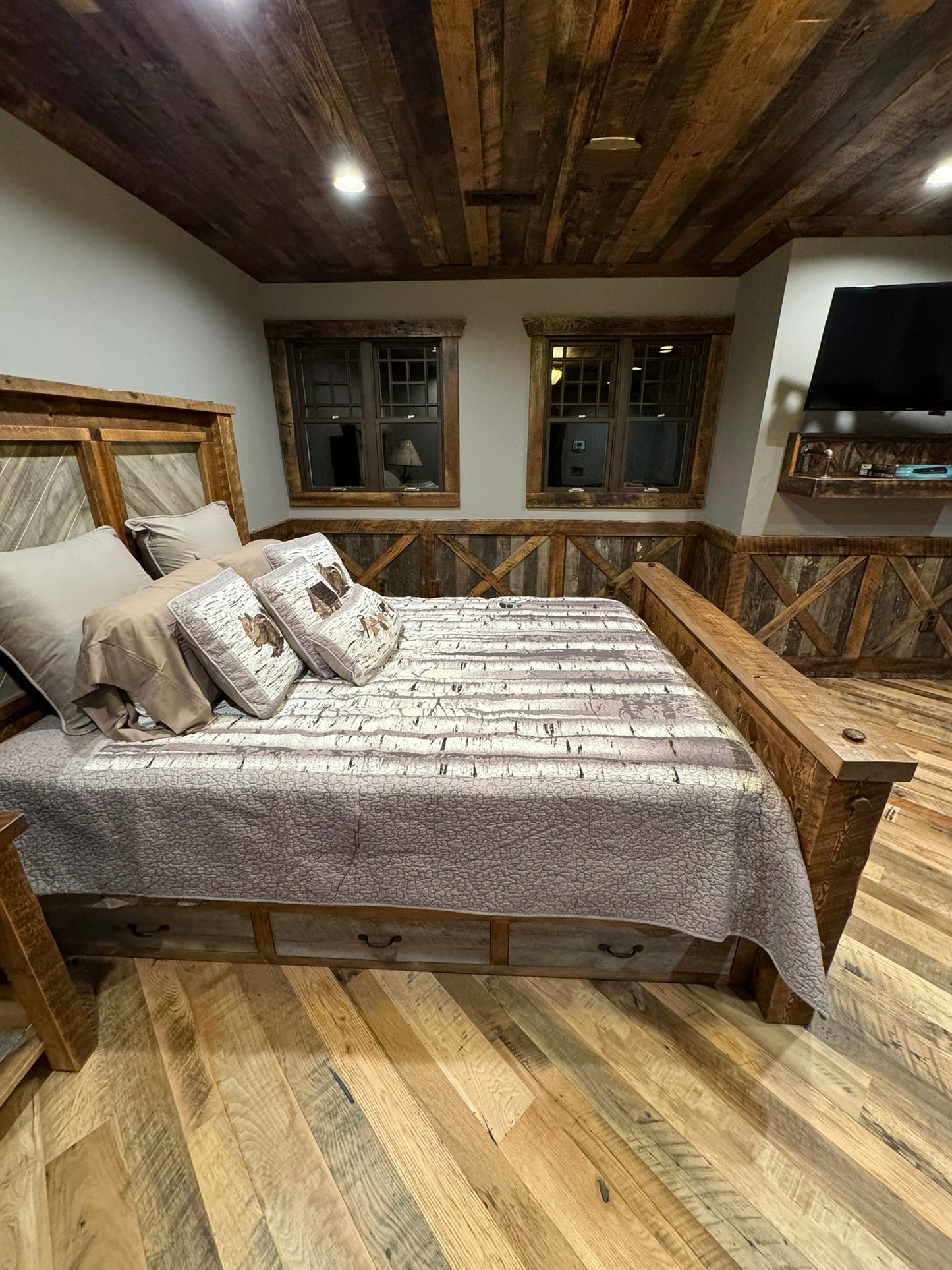 Heartland Barnwood Mixed Hardwoods Skip-Planed Brown flooring used in bed room with wood panel ceiling and wood wall trim.