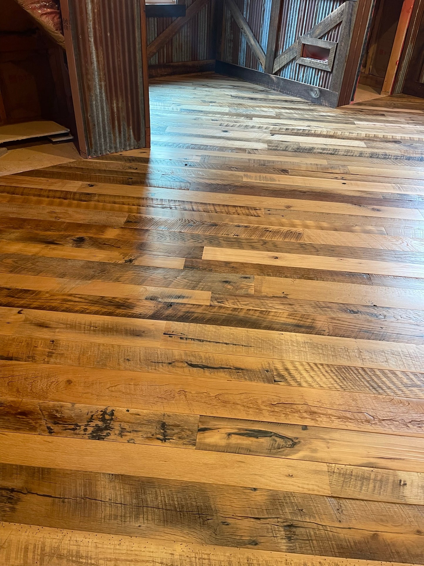 Close up of Heartland Barnwood Mixed Hardwoods Skip-Planed Brown flooring and wood wall trim in barn style room 2