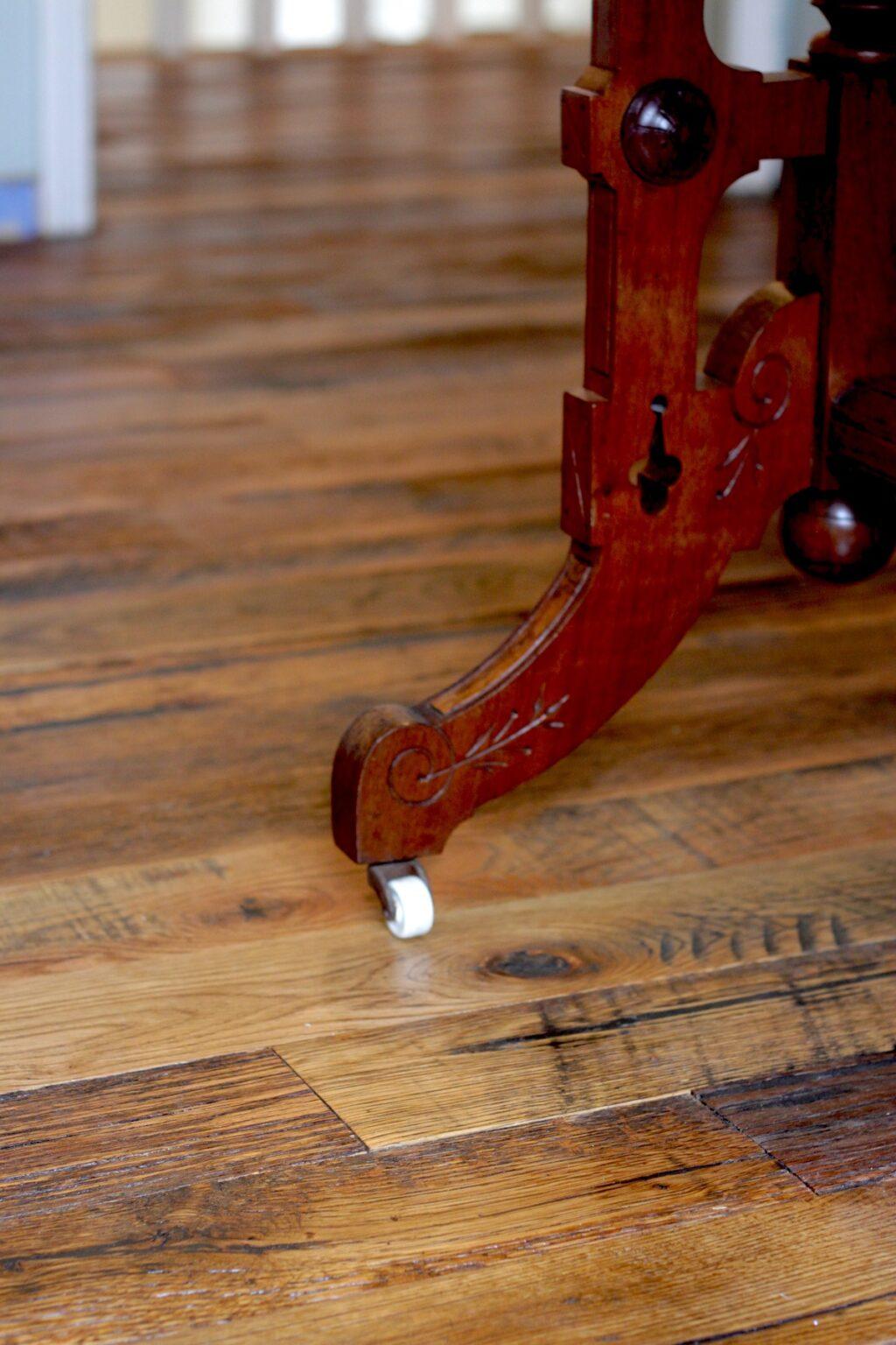 close up of Racehorse Oak Red & White Mix Skip/Wire-Brushed flooring and wood table leg