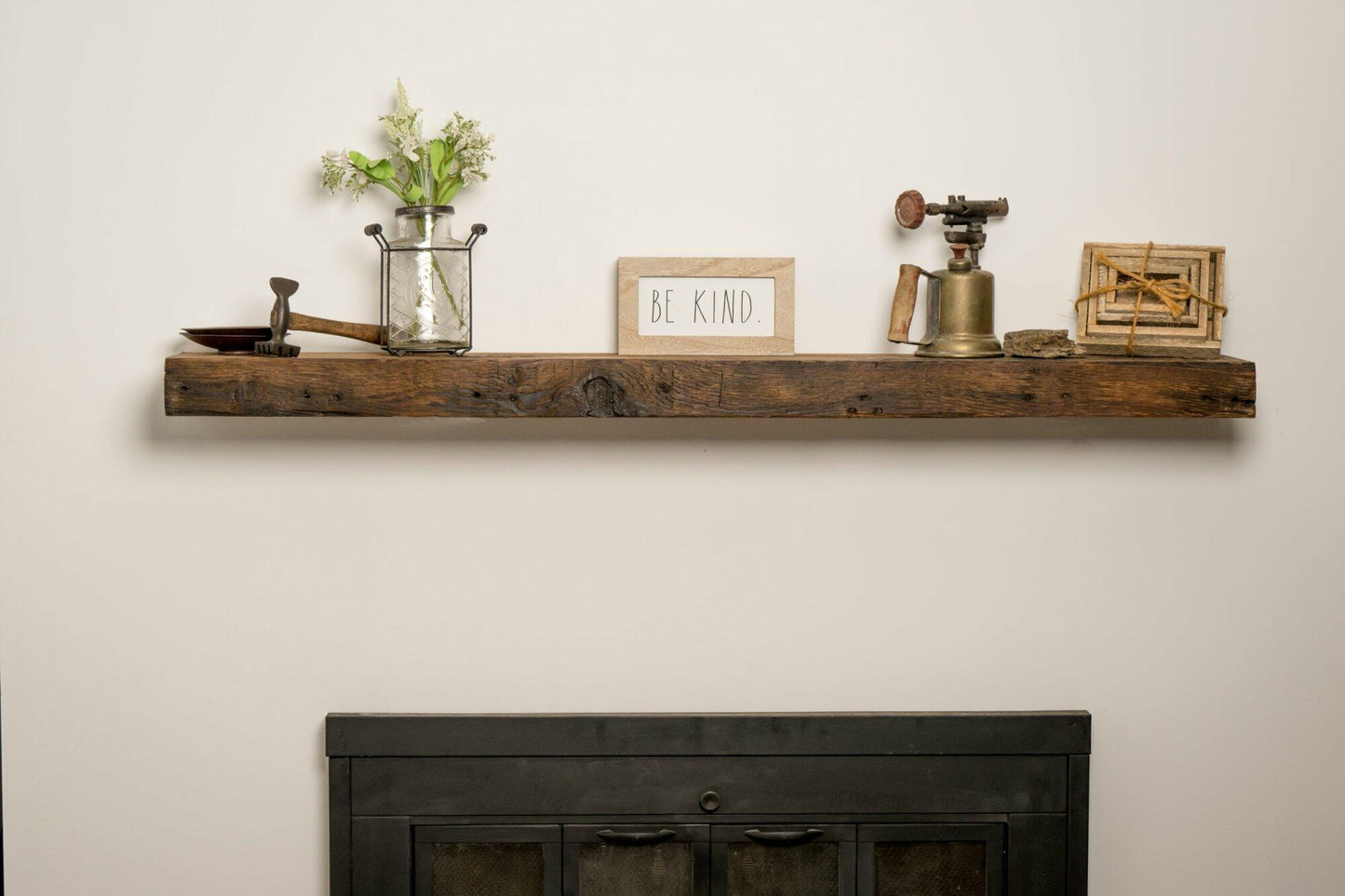 reclaimed wood floating fireplace mantel in the oil finish. Mantel is shown over a fireplace and decorated. Characteristics shown in the mantel are nail holes, knots, and grain patterns.