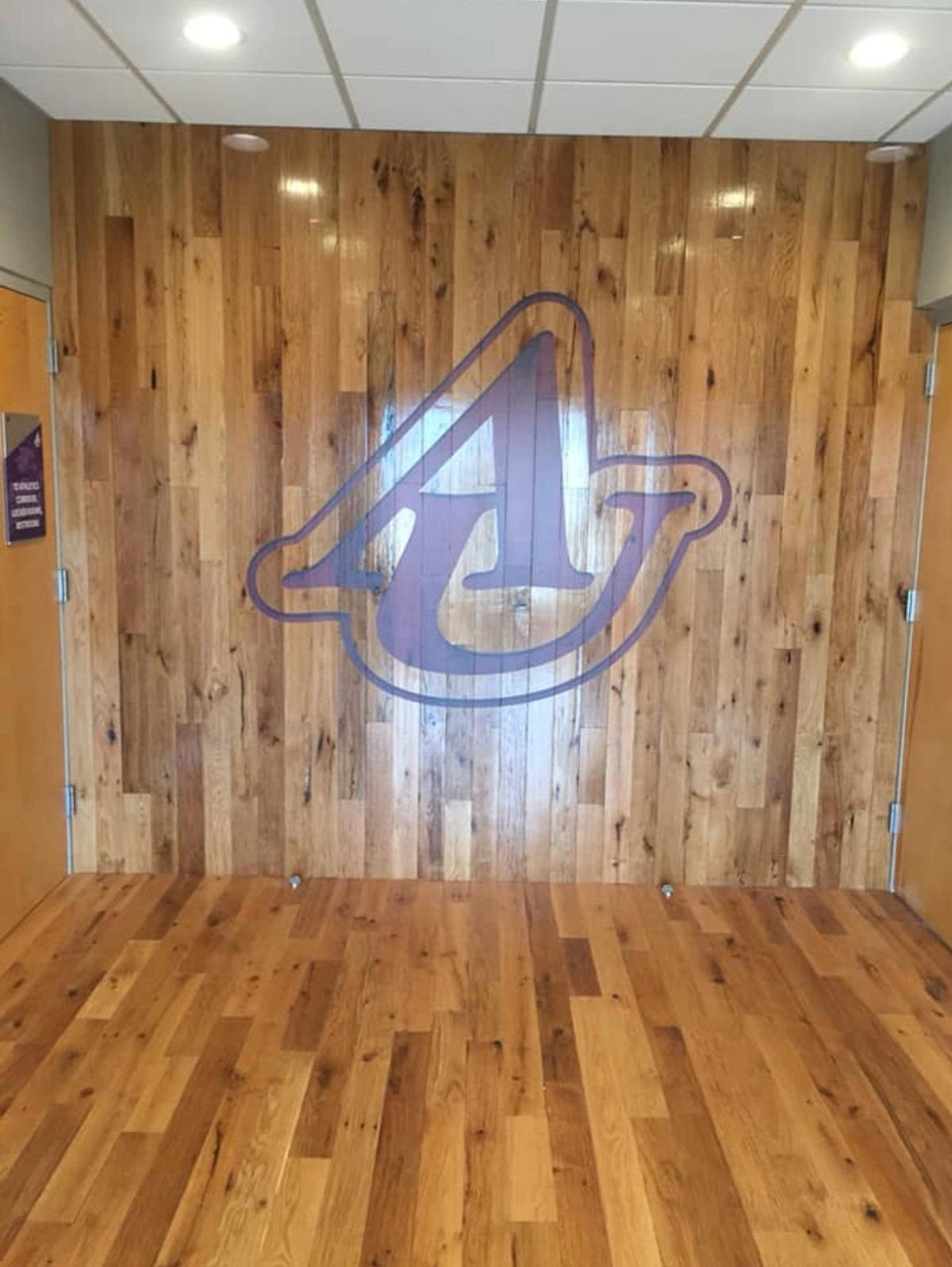 Racehorse Oak Red & White Mix Clean Face wood flooring and wall paneling used in a university common area with logo on wall.