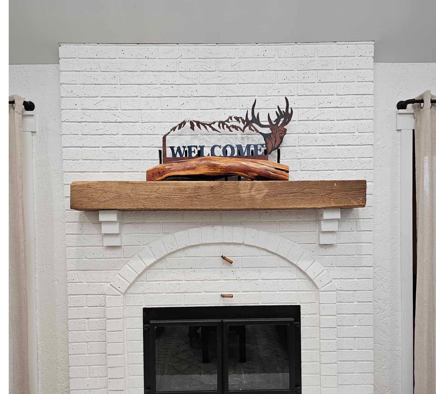 Reclaimed Wood Floating Fireplace Mantel mounted above fireplace with welcome decoration on mantel