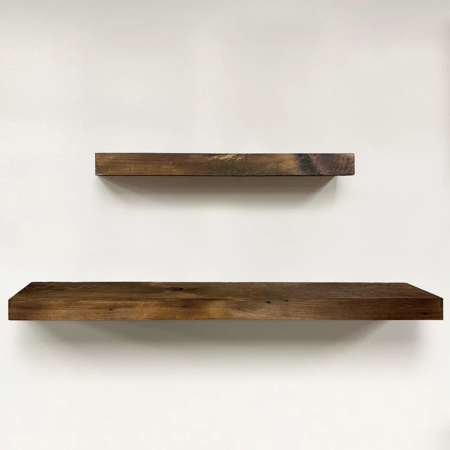 a set of two reclaimed wood floating shelves in the early american finish. Variations in wood color, knots, and grain patterns are present in the wood.