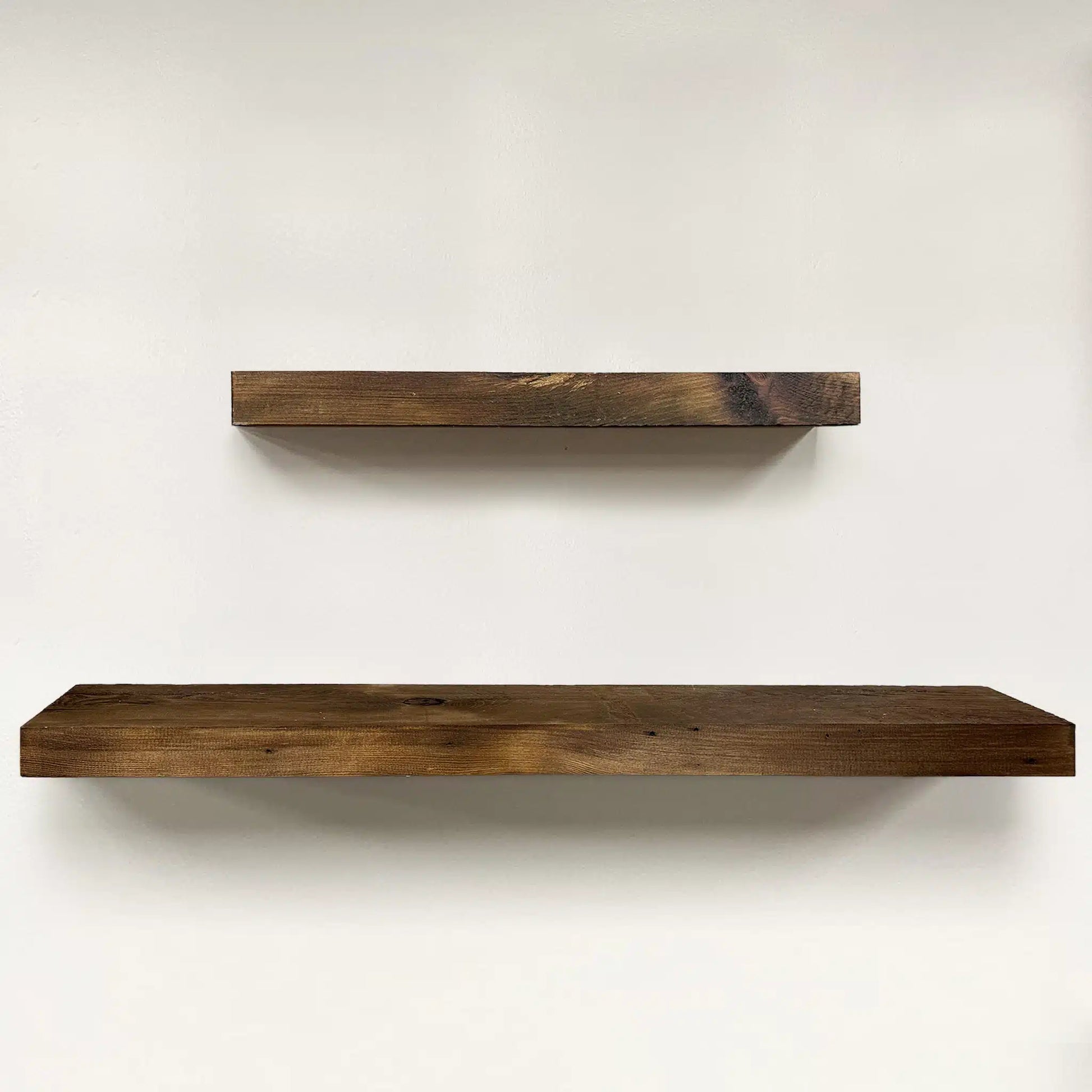 a set of two reclaimed wood floating shelves in the early american finish. Variations in wood color, knots, and grain patterns are present in the wood.