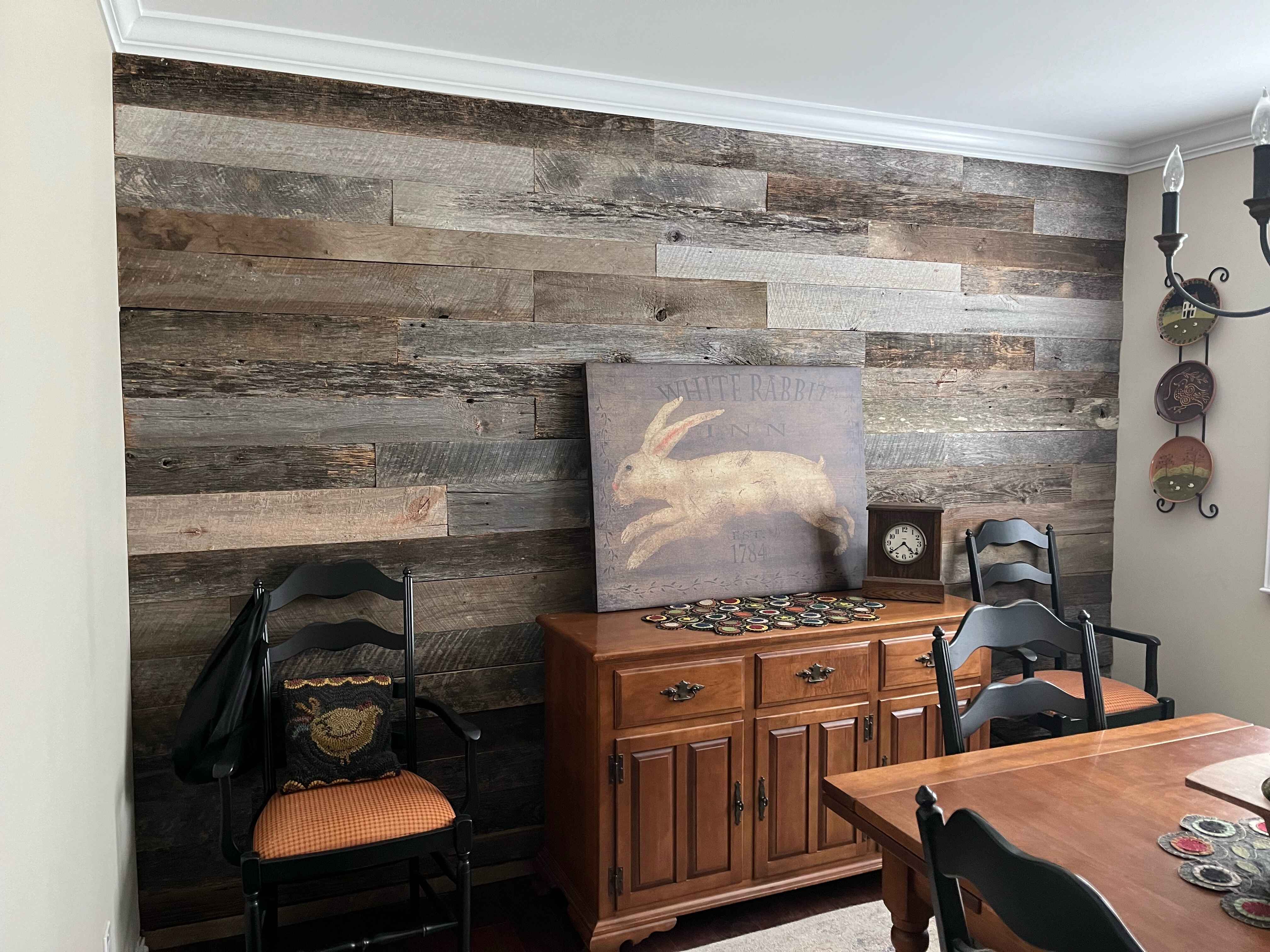 Weathered Grey Barnwood Paneling | Reclaimed Wood Wall planks on accent wall with wooden dresser with painting on top and chairs on either side