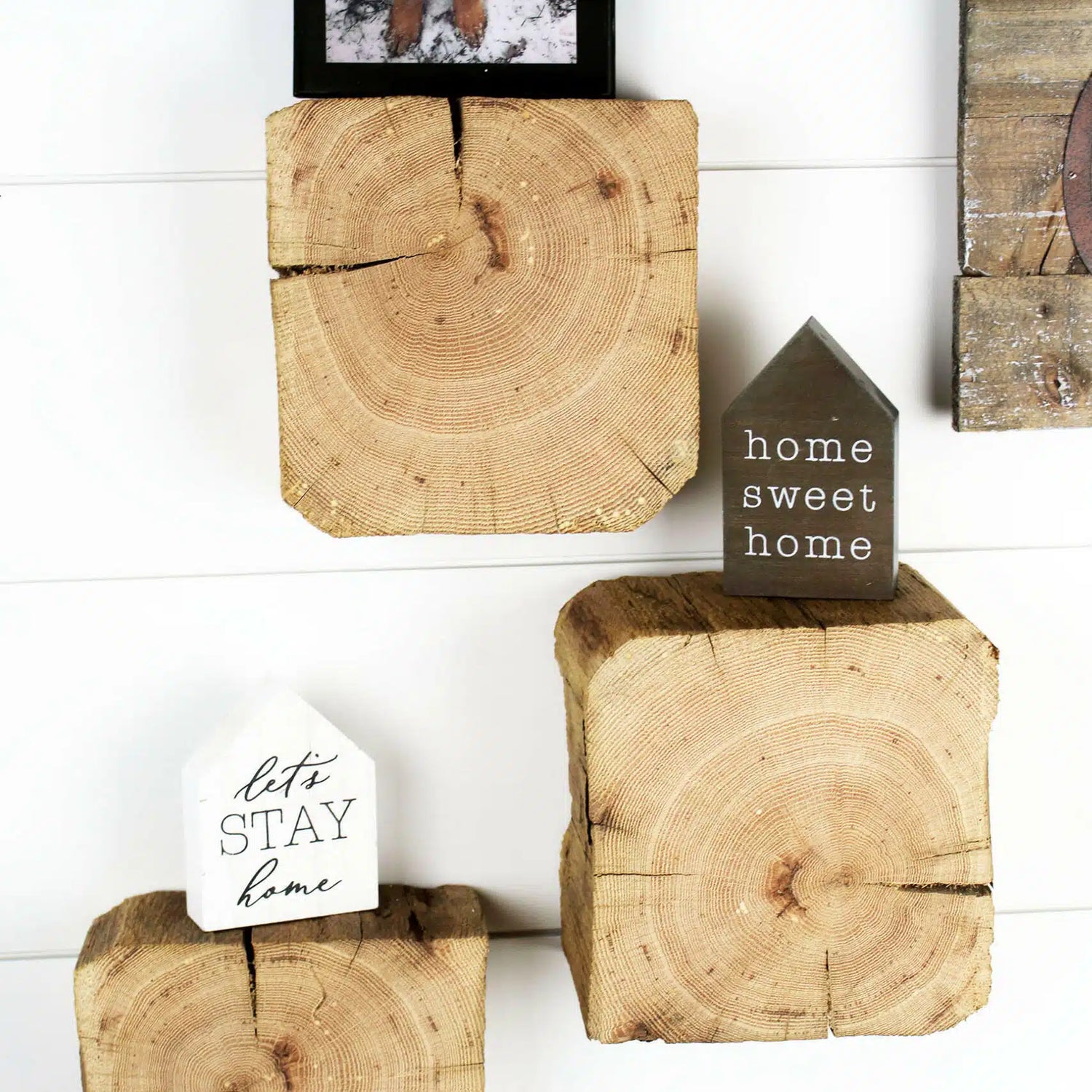a set of three reclaimed wood wall blocks. The front facing sides are a fresh cut end displaying the growth rings and checking in the wood. The three blocks are staggered on the wall with minimal decor.