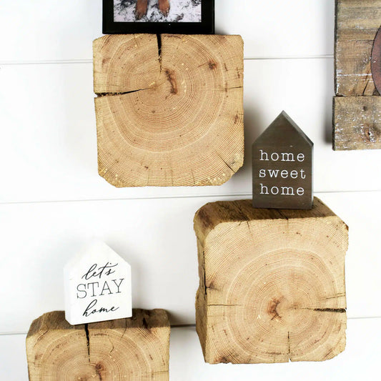 a set of three reclaimed wood wall blocks. The front facing sides are a fresh cut end displaying the growth rings and checking in the wood. The three blocks are staggered on the wall with minimal decor.