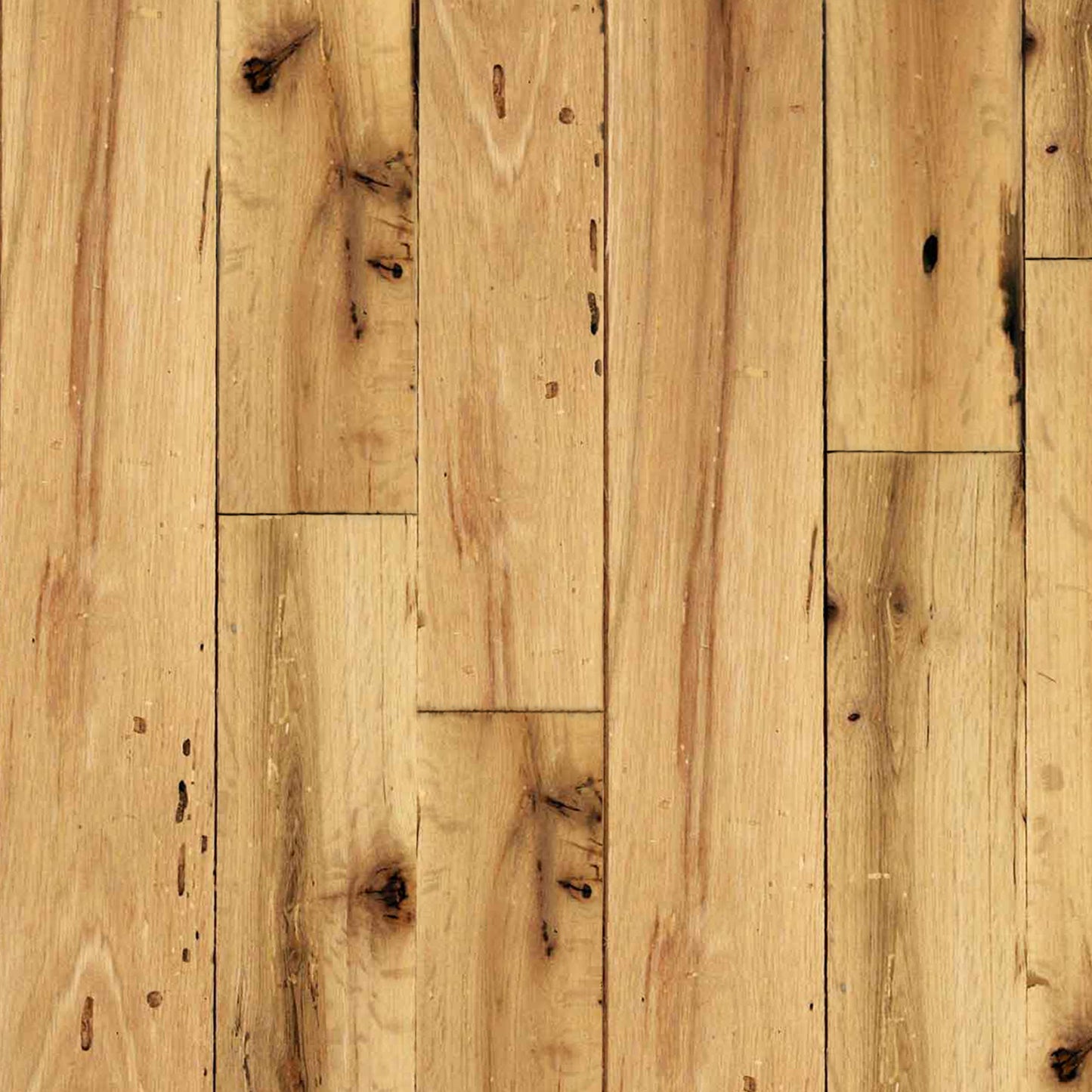 close up of red oak reclaimed flooring installed. Variations in wood color and grain pattern, knots, and characteristics from previous bug activity shown.