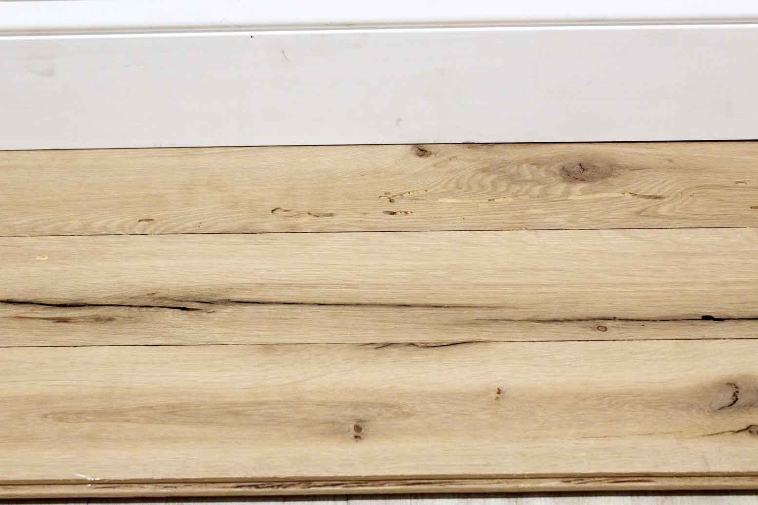 reclaimed white oak flooring installed with baseboard molding. Variations in wood color shown along with knots, checking, and characteristics from previous bug activity.