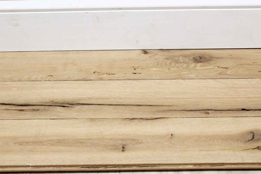 close up of reclaimed white oak flooring installed. Variations in wood color shown along with knots, checking, and characteristics from previous bug activity.