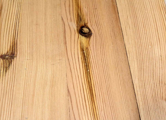 close up of yellow pine reclaimed flooring installed. There are a sizeable number of knots shown throughout and grain patterns in the wood are prominent.