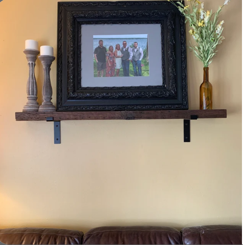 reclaimed barnwood wall shelf with custom brackets displayed in a living room.