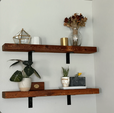 two reclaimed barnwood wall shelves with L shaped angle brackets. Shown in an oil finish that highlights the grain patterns and nail holes in the wood.