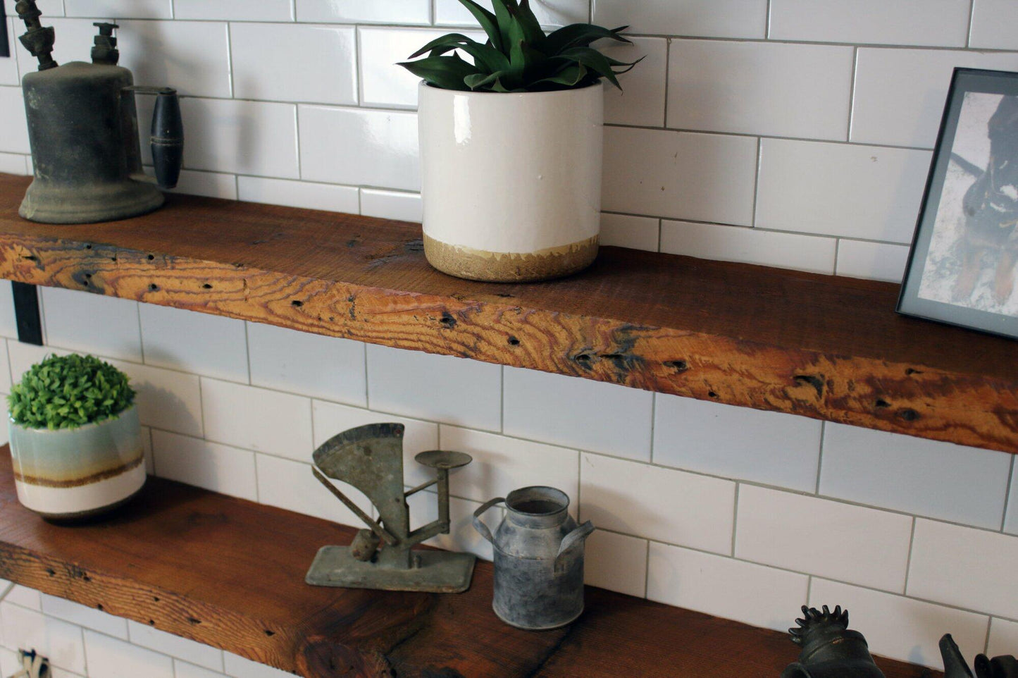 two reclaimed barnwood wall shelves shown close up from a top view. The shelves are shown in the oil finish which highlights the grain patterns and variations in the wood. Nail holes and knots are also displayed in the shelves.