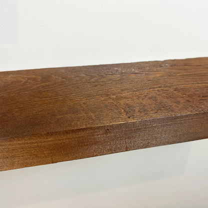 a close up of a reclaimed wood floating shelf in the early american finish showing the grain pattern and texture.