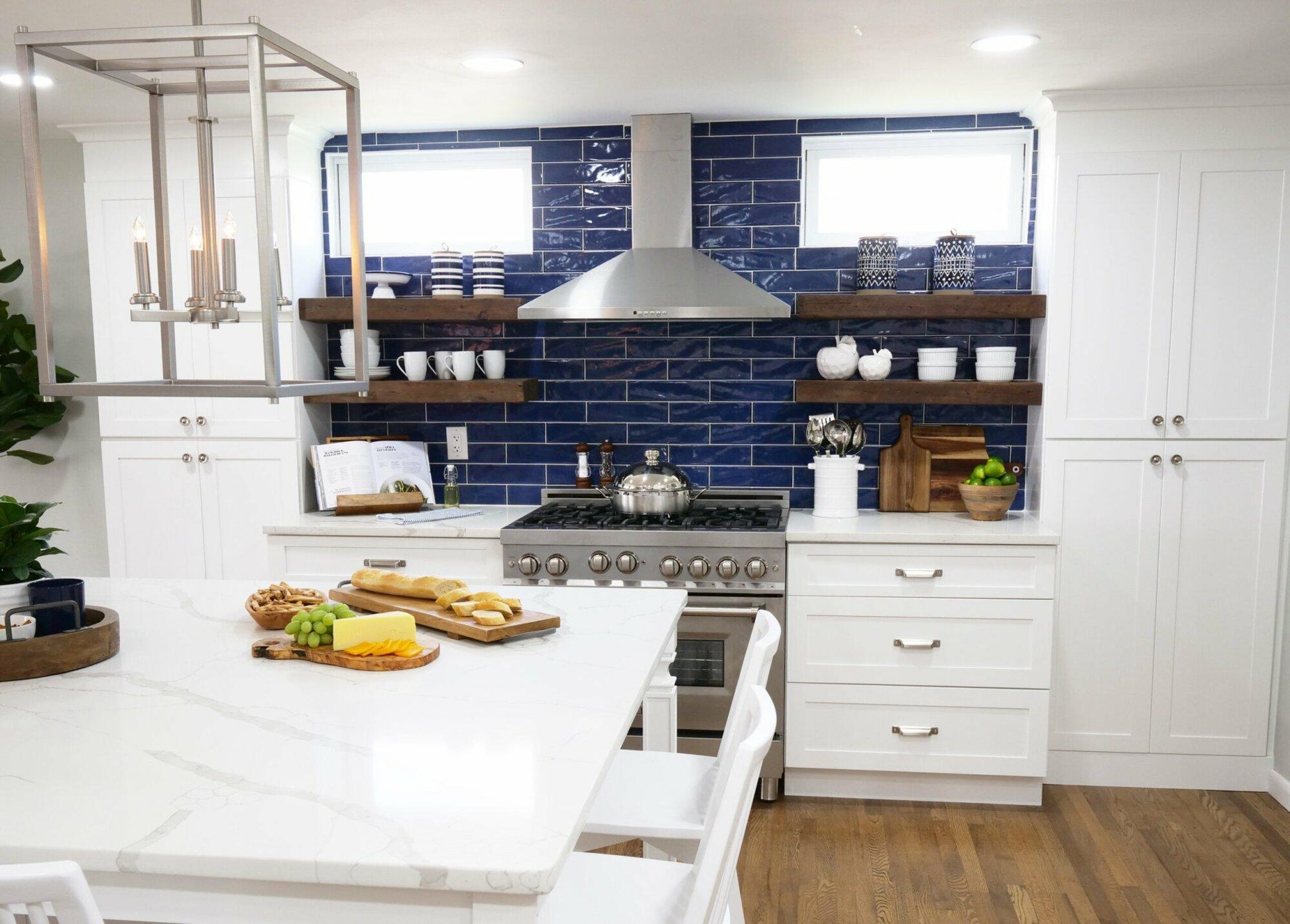 floating reclaimed barnwood shelves in a kitchen. Four shelves are displayed on a subway tile backsplash supporting dishes, glasses, and vases.