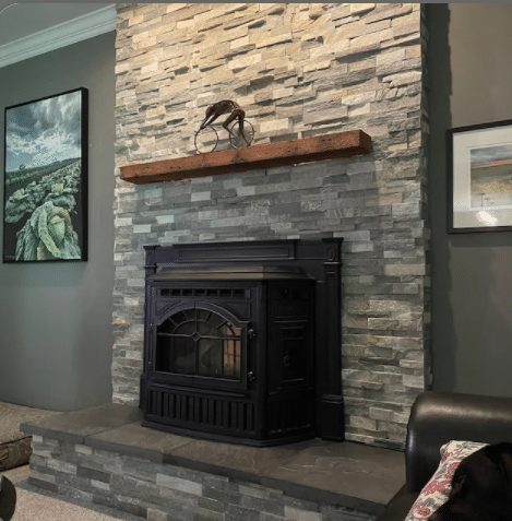 reclaimed barnwood fireplace mantel floating on a stone fireplace. Nail holes displayed and minimal decor displayed on the middle of the mantel.