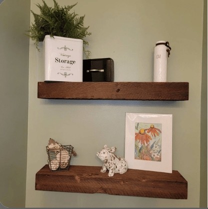 two reclaimed barnwood floating shelves on a wall. Grain pattern is displayed with other distressed characteristics.