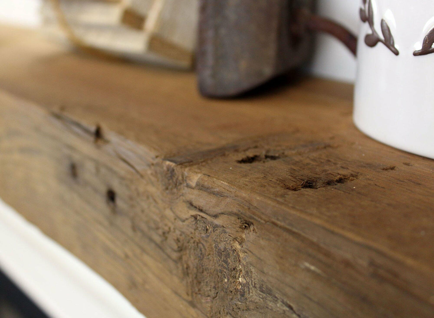 close up of the front face of a skip-planed reclaimed barnwood fireplace mantel. Close up shows knots, wood texture, and other authentic characteristics.