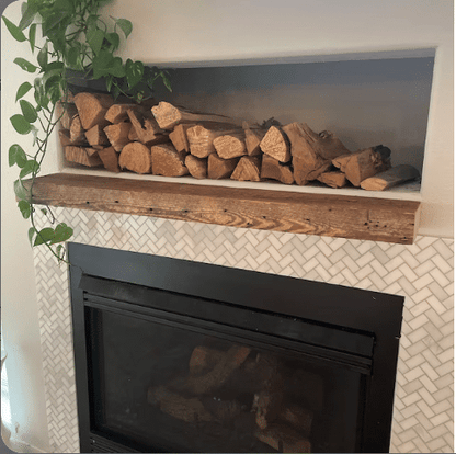 a reclaimed barnwood floating fireplace mantel. Shown natural on a stone fireplace with nail holes and grain patterns displayed.