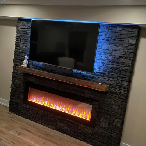 reclaimed barnwood fireplace floating mantel on a dark stone fireplace. There is a backlit television mounted above and a lit fireplace below for ambiance.