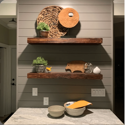 two reclaimed barnwood floating shelves on a shiplap wall in an oil finish. Knots and grain patterns highlighted from the oil finish.