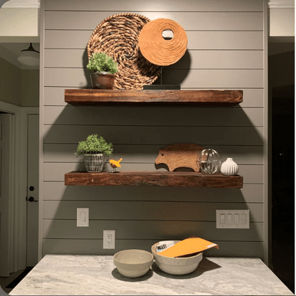 two reclaimed barnwood floating shelves on a shiplap wall in an oil finish. Knots and grain patterns highlighted from the oil finish.