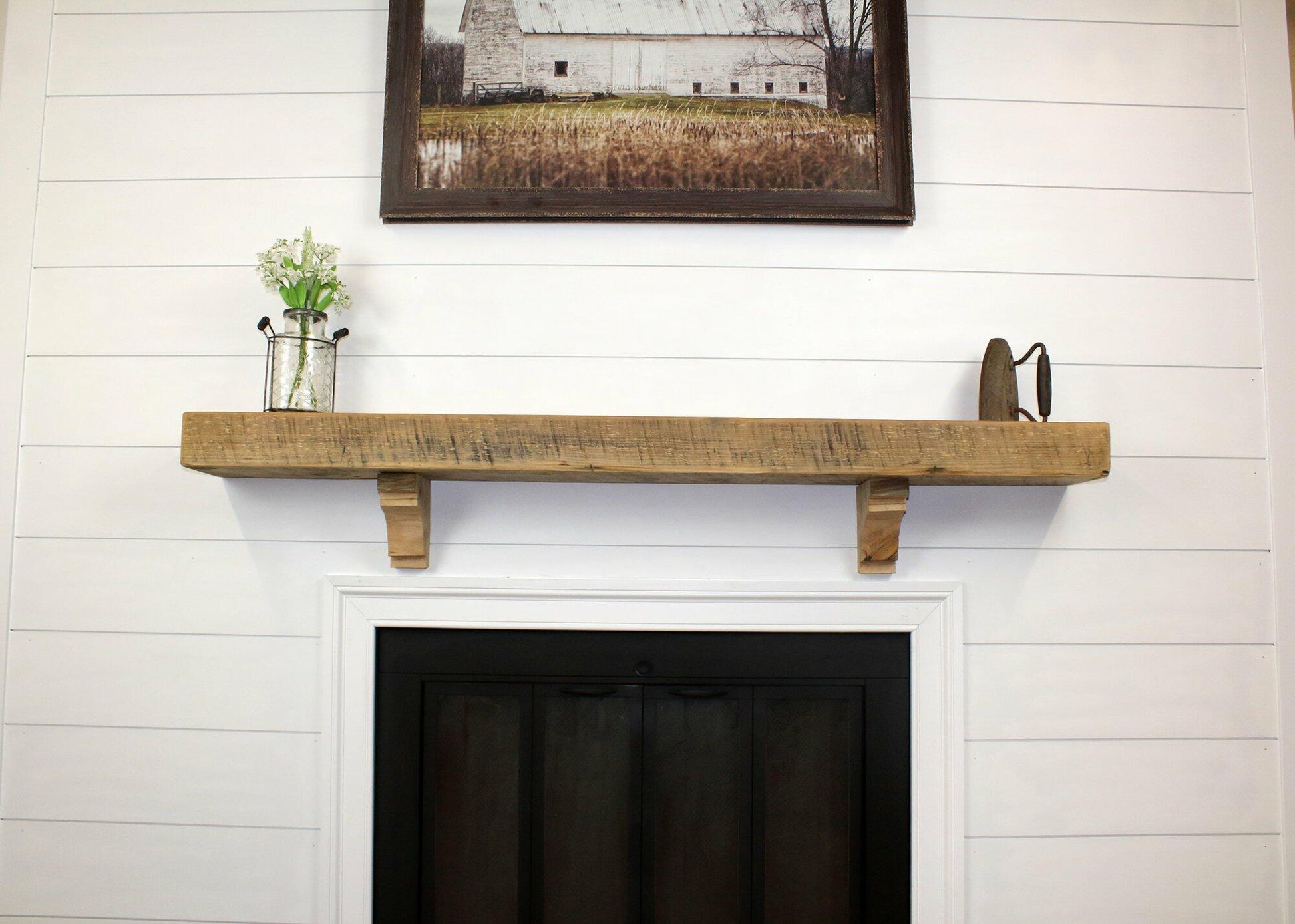 a reclaimed wood floating fireplace mantel in the natural option. The mantel has matching corbels shown underneath and has prominent saw markings in the face.
