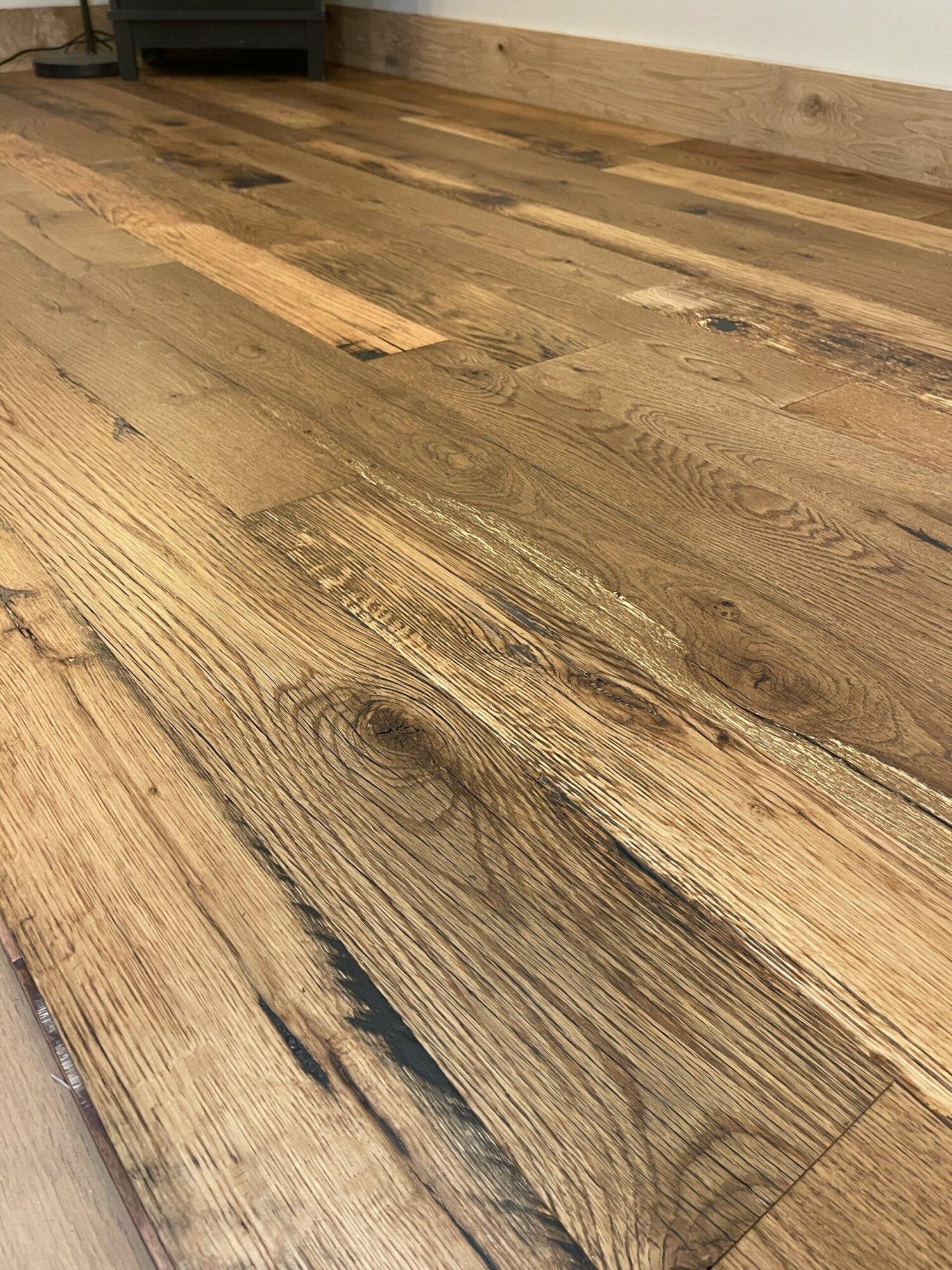 close up of Reclaimed Kentucky Race Horse Fence Plank flooring showing various color tones and characteristics of reclaimed wood such as grain patterns and knots.