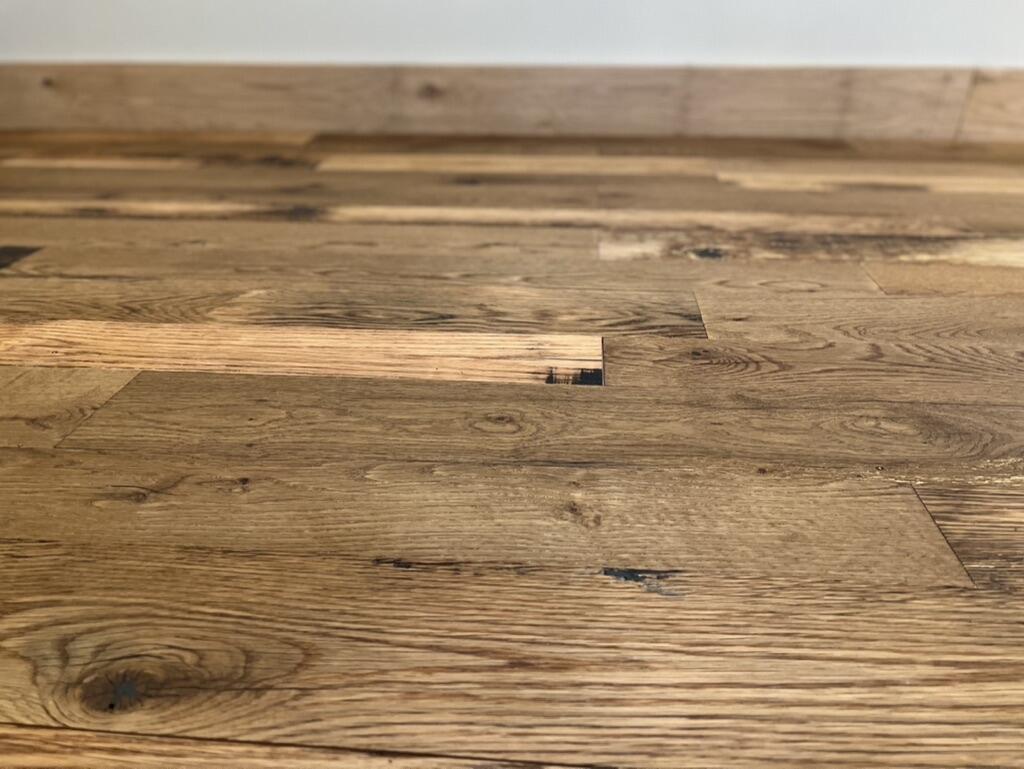 close up of Reclaimed Kentucky Race Horse Fence Plank flooring showing various color tones and characteristics of reclaimed wood such as grain patterns and knots.