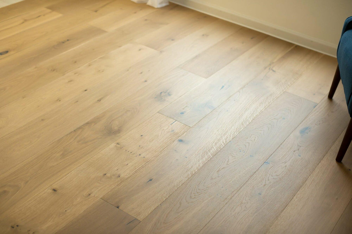 close up of engineered white oak wide plank flooring. With a UV Lacquer Matte finish, the ends of each piece are tongue and grooved for an easy install. Each piece of flooring shows knots and other subtle variations. This finished engineered hardwood has square edges and square ends.