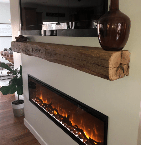 natural wood colored, hand hewn beam that is rounded similar to a log. Mantel shows natural characteristic called checking which is similar to cracking and axe marks along the front.