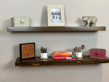 two reclaimed wood floating wall shelves in the contemporary collection and jacobean finish. Bottom shelf has prominent highlighted grain patterns in the wood. Both shelves have a shine on them from the lacquer application.