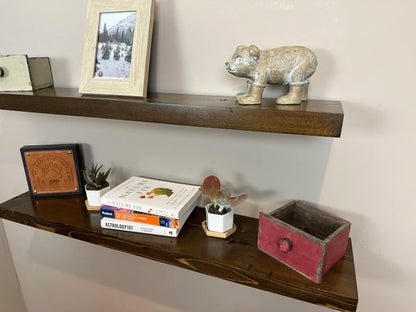 two reclaimed wood floating wall shelves in the contemporary collection and jacobean finish. Bottom shelf has prominent highlighted grain patterns in the wood. Both shelves have a shine on them from the lacquer application.