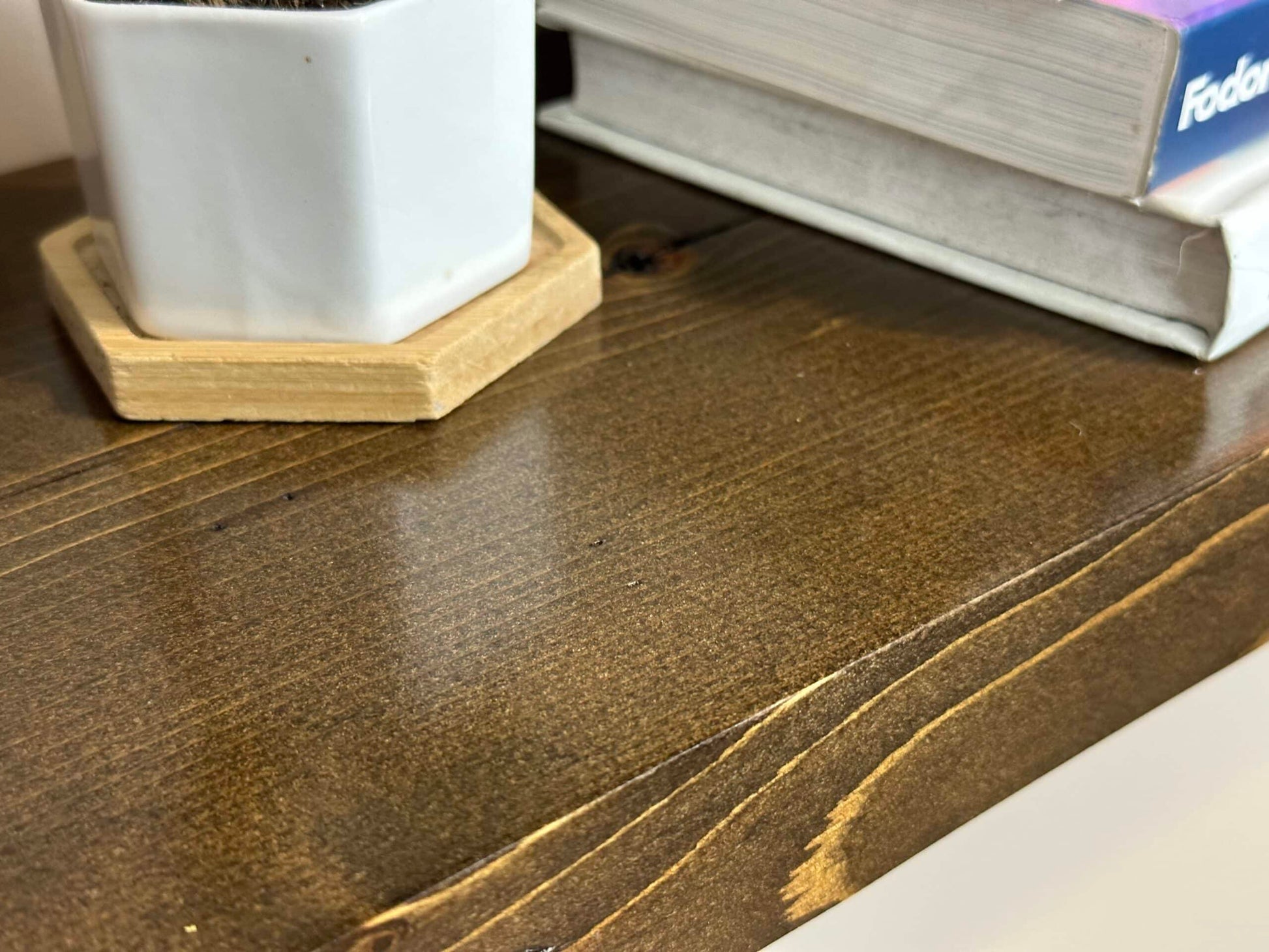 a close up of the finish on a reclaimed wood floating shelf in the contemporary collection. The lacquer application adds a shine and smoothness to the wood. Grain patterns are present and highlighted in the wood.
