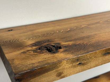 a close up of a shelf showing variation in wood color, a large knot, grain patterns, and nail holes in the wood.
