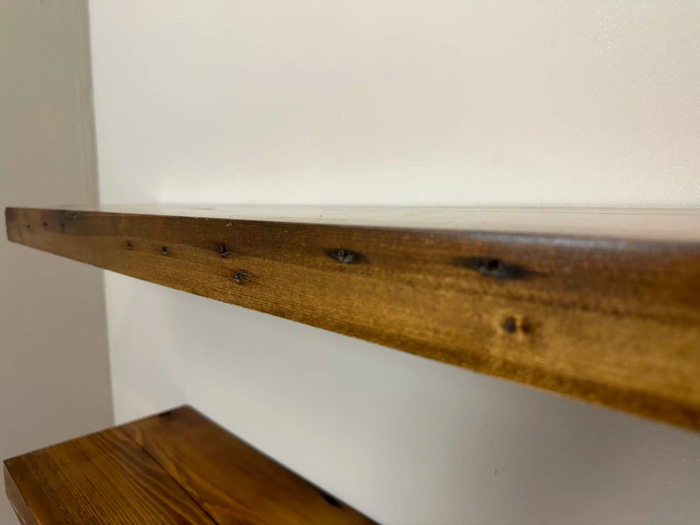 a close up of the front edge of a shelf in the contemporary collection. The face of the shelf has color variations and nail holes present.
