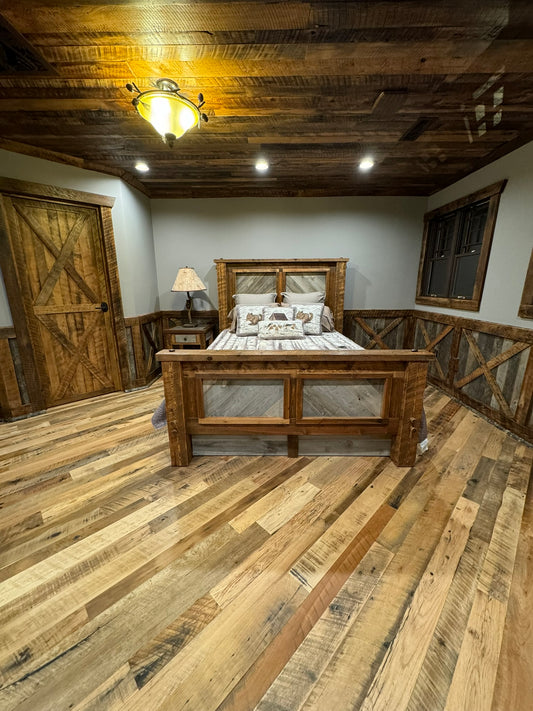 Heartland Barnwood Mixed Hardwoods Skip-Planed Brown flooring used in bed room with wood panel ceiling and wood wall trim. 