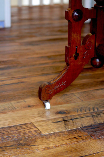 close up of Racehorse Oak Red & White Mix Skip/Wire-Brushed flooring  and wood table leg