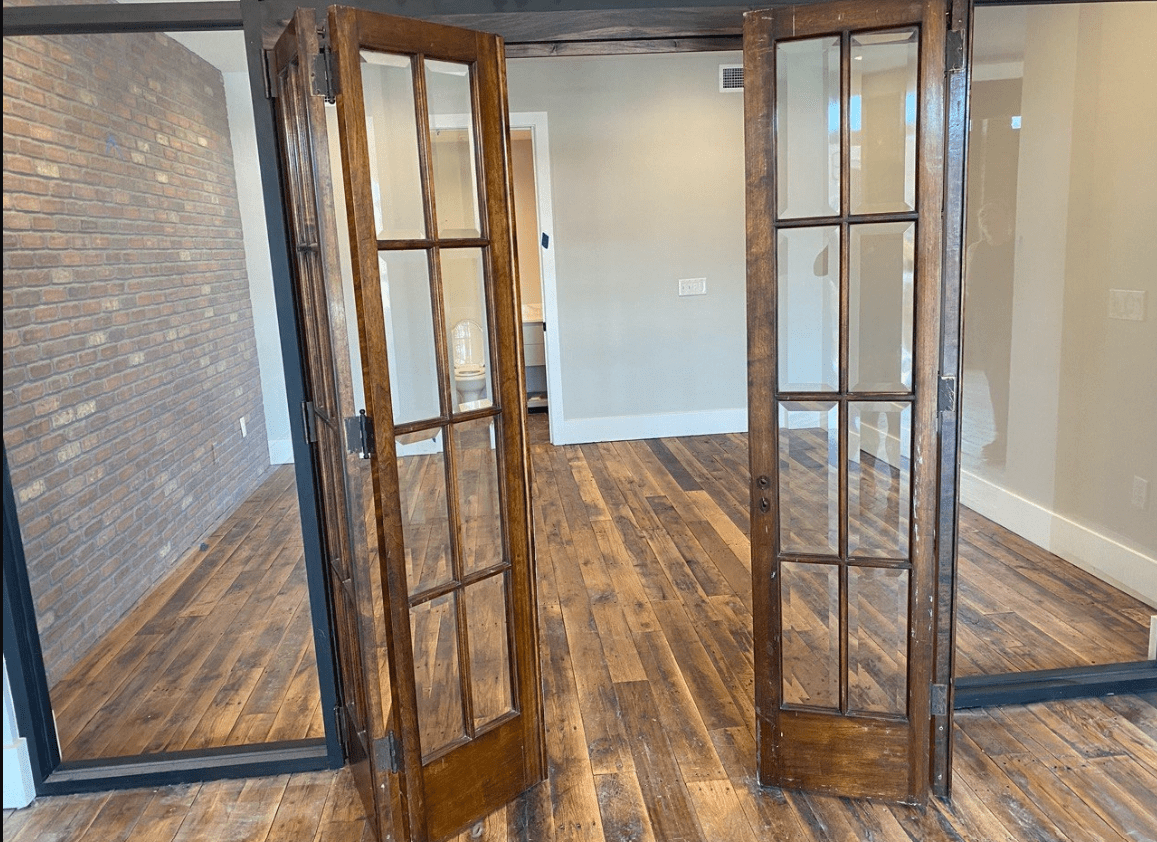 Reclaimed Industrial Oak Engineered Flooring in common area with wood doors and full wall glass