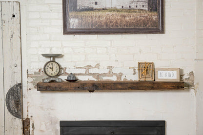 reclaimed barnwood floating fireplace mantel in an oil finish. Displayed on a brick and concrete fireplace with knots, nail holes, and grain patterns present.