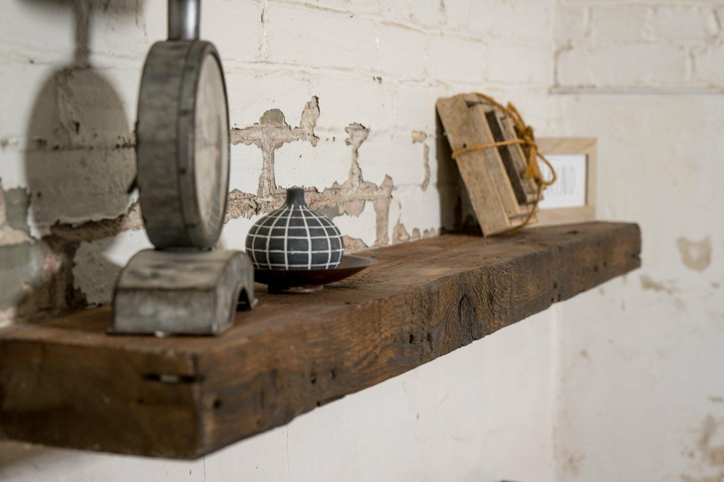 reclaimed barnwood floating fireplace mantel in an oil finish. Displayed on a brick and concrete fireplace with knots, nail holes, and grain patterns present.