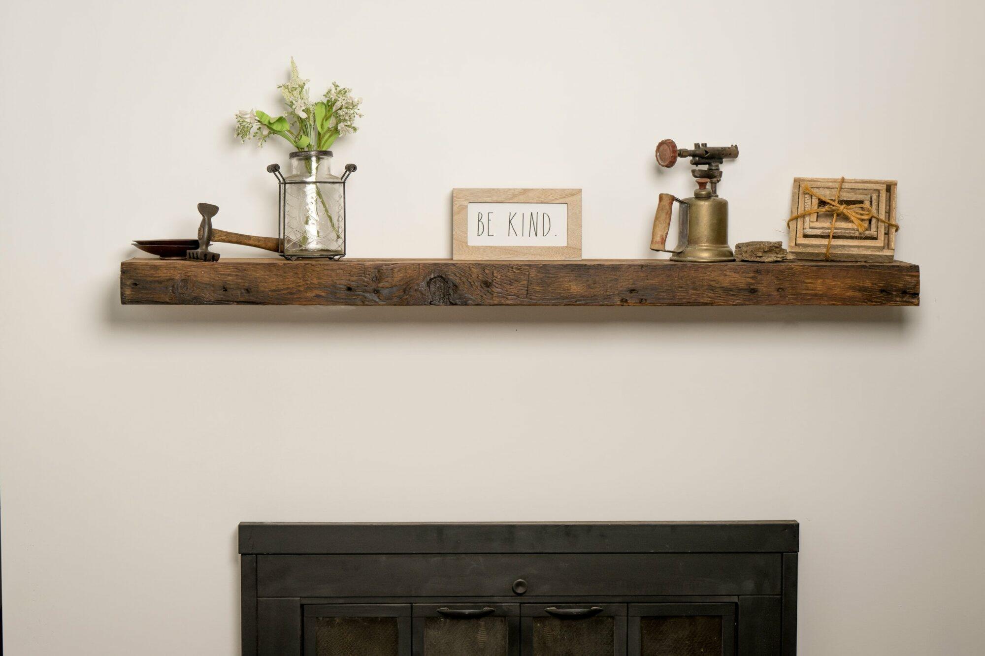 reclaimed wood floating fireplace mantel in the oil finish. Mantel is shown over a fireplace and decorated. Characteristics shown in the mantel are nail holes, knots, and grain patterns.