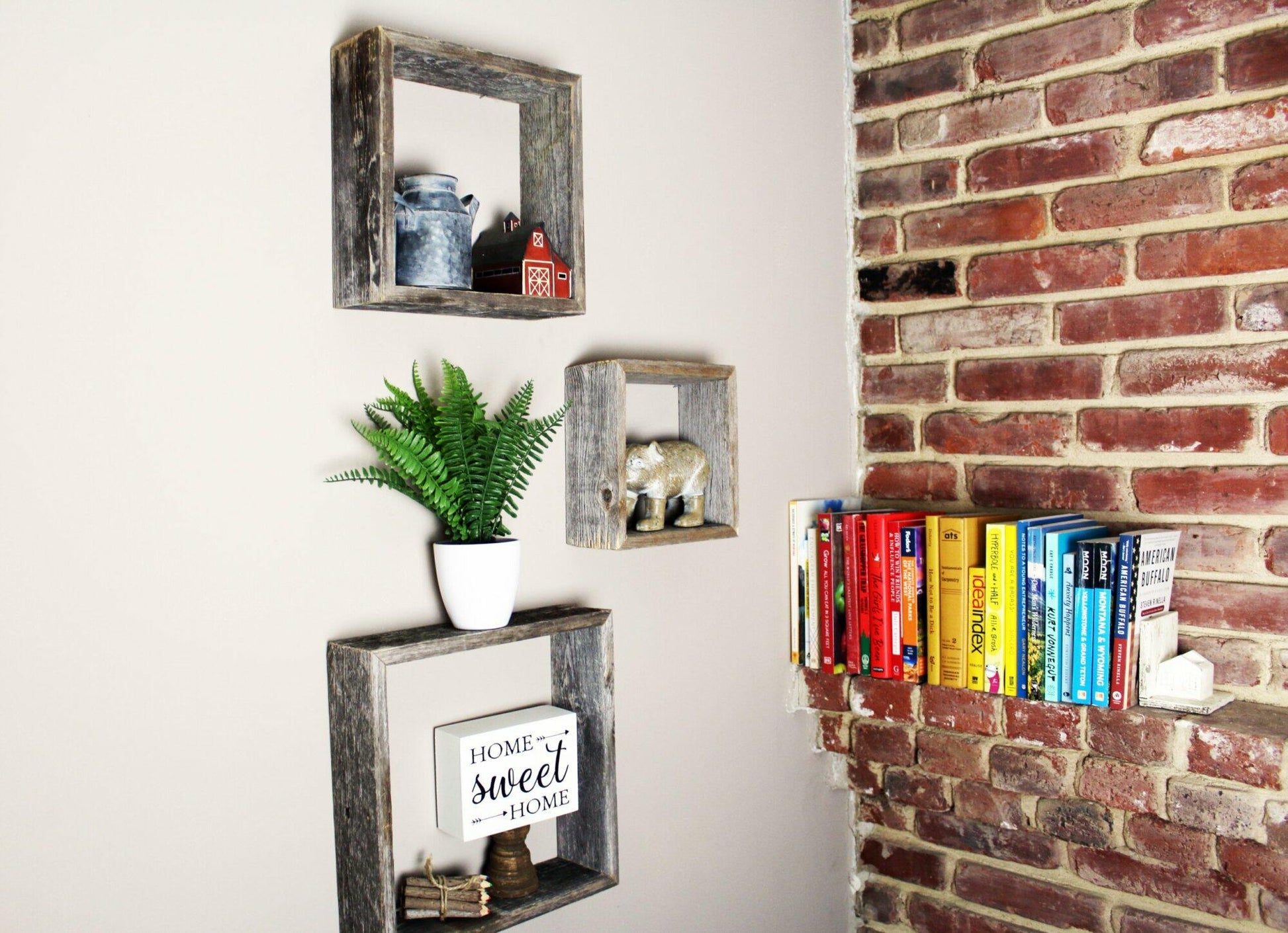 three open box floating shelves in small, medium, and large sizes. Open box shelves shown decorated on a wall next to a brick wall with books displayed.