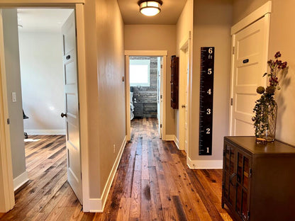 Racehorse Oak Red & White Mix Skip/Wire-Brushed flooring in common area looking into two rooms with open doors with wood flooring