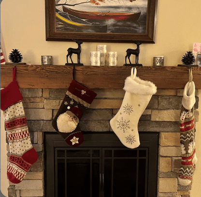 a reclaimed wood rustic fireplace mantel. The mantel is installed over a stone fireplace and decorated for the Christmas holiday with stockings. The grain pattern is prevalent in the mantel.